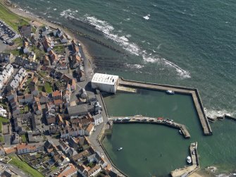 Oblique aerial view centred on the boathouse/boatshed with the harbour adjacent, taken from the W.