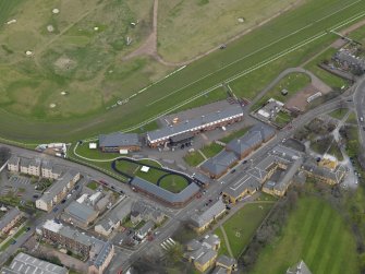 Oblique aerial view centred on the race course grandstands with the paddock adjacent, taken from the SW.