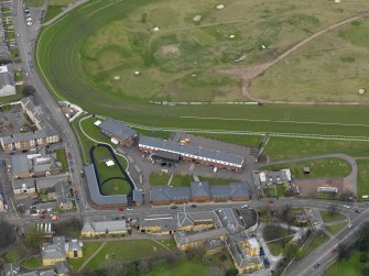 Oblique aerial view centred on the race course grandstands with the paddock adjacent, taken from the SSW.