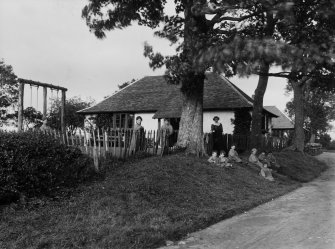 View of single-storey building on the Montgreenan House estate, showing children sitting outside.