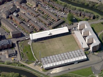 Oblique aerial view centred on the football ground with the apartment block adjacent, taken from the E.