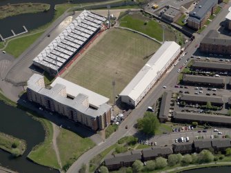 Oblique aerial view centred on the football ground with the apartment block adjacent, taken from the NW.