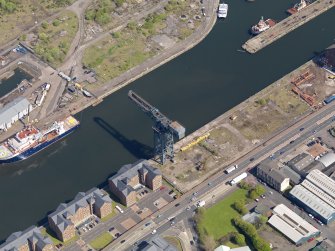 Oblique aerial view centred on the dock with the crane adjacent, taken from the SW.