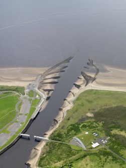 Oblique aerial view centred on the footbridge and breakwaters with the visitor centre adjacent, taken from the NNE.