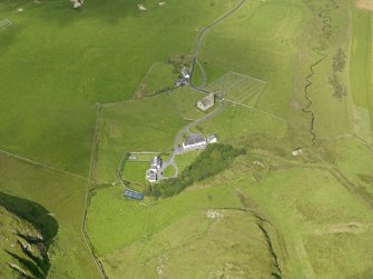 Oblique aerial view centred on the church, cemetery, manse and house at Kilchoman, Islay, taken from the SE.