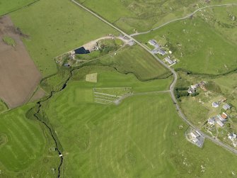 Oblique aerial view centred on the cemetery and the remains of the chapel at Nerabus, Islay, taken from the E..