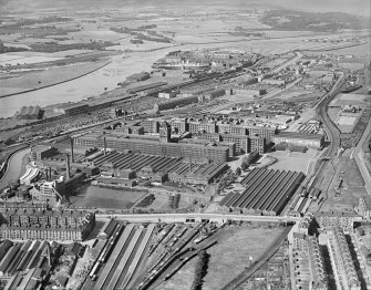 Oblique aerial view centred on Singer Sewing Factory, Clydebank, with the railway station adjacent with John Brown's shipbuilding yard in the background, taken from the E.
