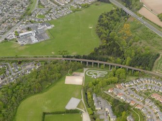 Oblique aerial view centred on the railway viaduct with the school adjacent, taken from the SE.