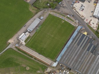 Oblique aerial view centred on the football ground with the auction mart adjacent, taken from the WSW.
