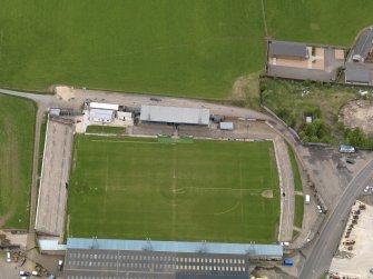 Oblique aerial view centred on the football ground with the auction mart adjacent, taken from the S.