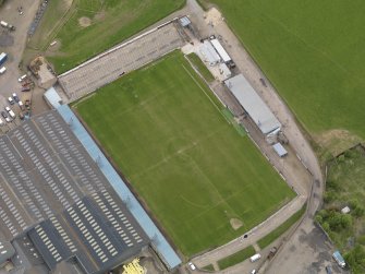 Oblique aerial view centred on the football ground with the auction mart adjacent, taken from the SE.