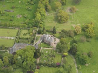 Oblique aerial view of the tower house with the gardens and stables adjacent, taken from the WSW.