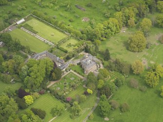 Oblique aerial view of the tower house with the gardens and stables adjacent, taken from the SW.
