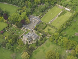 Oblique aerial view of the tower house with the gardens and stables adjacent, taken from the SSE.
