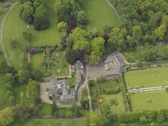 Oblique aerial view of the tower house with the gardens and stables adjacent, taken from the E.