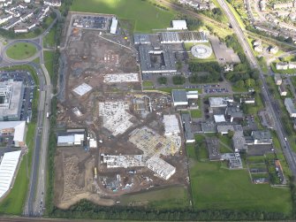 Oblique aerial view centred on the construction site for new Forrester Secondary and St Augustine RC High schools, with the original schools to the E.