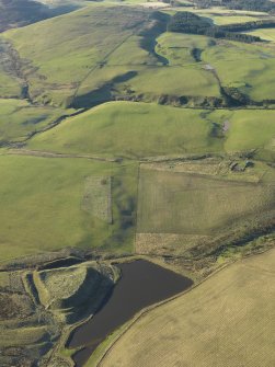 General oblique aerial view of the remains of Green Castle fort and rig in the foreground with Park Burn fort and rectilinear settlement in the distance, taken from the NE.