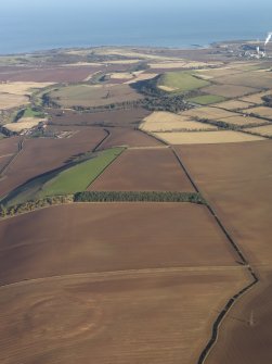 General oblique aerial view of the soilmarks of the fort of The Chesters, Spott, with the coast in the distance, taken from the SW.