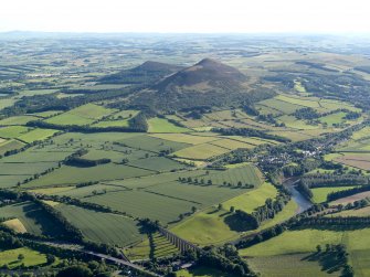 General oblique aerial view looking across the bridge, viaduct, village and site of the Roman fort  towards the fort and Eildon Hills, taken from the NE.