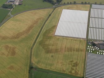 Oblique aerial view centred on the cropmarks of the rig, pits, enclosure, round house and souterrains at Hatton Farm, taken from the WNW.