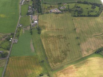 Oblique aerial view of the cropmarks of the round houses, ring ditches and rig and furrow with Hedderwick House adjacent, taken from the WSW.