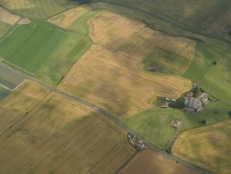 Oblique aerial view of the cropmarks of the barrow, ring ditches and pits at Easter Kinnear with the farmsteading adjacent, taken from the WNW.