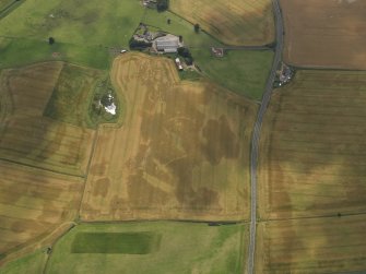 Oblique aerial view of the cropmarks of the barrow, ring ditches and pits at Easter Kinnear with the farmsteading adjacent, taken from the NE.