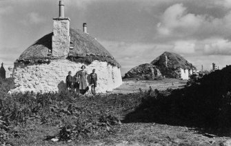 Side view of cottages at Liniclett, Benbecula with crofter's family.