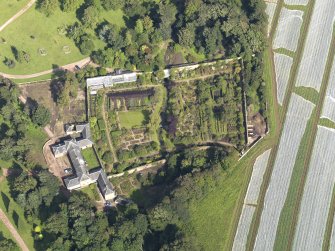 Oblique aerial view centred on the walled garden with the stables adjacent , taken from the S.