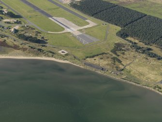 Oblique aerial view centred on the NE end of the main runway with a dispersal area adjacent, taken from the NE.