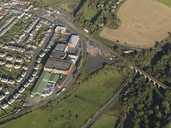 Oblique aerial view centred on the distillery with the railway viaduct adjacent, taken from the SW.