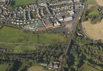 Oblique aerial view centred on the distillery with the railway viaduct adjacent, taken from the S.