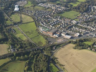 Oblique aerial view centred on the distillery with the railway viaduct adjacent, taken from the SE.