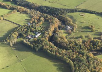 Oblique aerial view centred on the house with the stables adjacent, taken from the W.