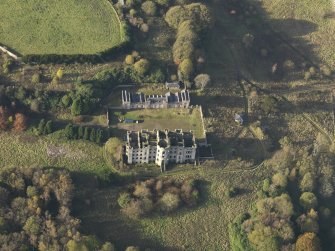 Oblique aerial view centred on the ruins of the country house with the stables adjacent, taken from the SE.