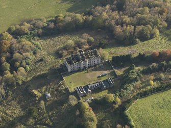 Oblique aerial view centred on the ruins of the country house with the stables adjacent, taken from the N.