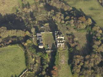 Oblique aerial view centred on the ruins of the country house with the stables adjacent, taken from the SW.