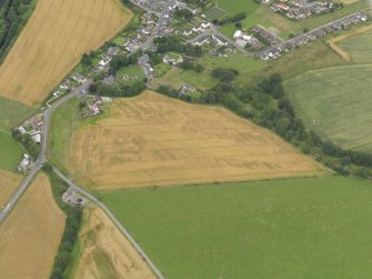 Oblique aerial view of the village of Marykirk and the cropmarks of the rig and furrow, unenclosed settlement and pits, taken from the SSW.