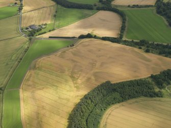 Oblique aerial view of the cropmarks of the quarry pits along the line of the Roman Road and the souterrains and unenclosed round houses at Wester Drumatherty, taken from the NW.