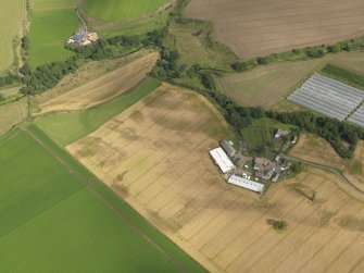 Oblique aerial view centred on the cropmarks of the enclosures, pits, henge, ring ditch and rig, taken from the NW.