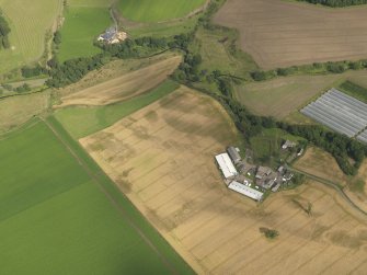 Oblique aerial view centred on the cropmarks of the enclosures, pits, henge, ring ditch and rig, taken from the WNW.