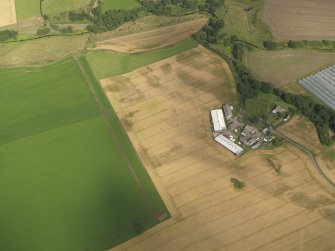 Oblique aerial view centred on the cropmarks of the enclosures, pits, henge, ring ditch and rig, taken from the W.