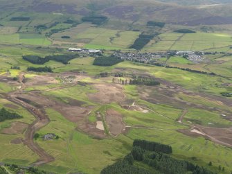 General oblique aerial view of the golf course under construction with Blackford village and The Ochils beyond, taken from the NNW.