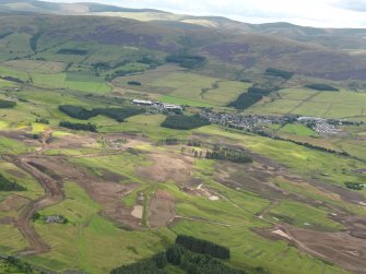 General oblique aerial view of the golf course under construction with Blackford village and The Ochils beyond, taken from the NNW.