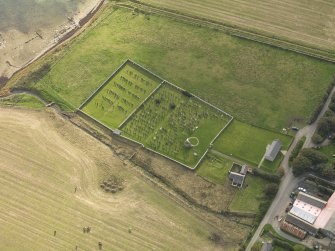 Oblique aerial view centred on the remains of the round church with the burial ground adjacent, taken from the NE.