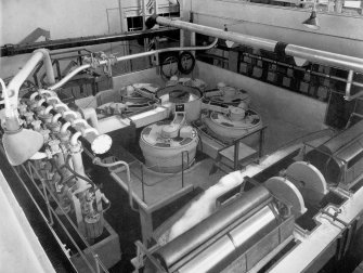 Copy of photograph of paper making machine (no.6), High Speed Refiners clear the stock. These units are manufactured by JBS under licence from ED JONES and Sons, Co., Pittsfield, USA and Drum Strainers made by JBS allowed the final screening of the stock to ensure good wire formation. The drums are 3 feet in diameter, from the JB&S Machine 161 catalogue, James Bertram and Son Ltd, Leith Walk, Edinburgh, circa 1953. The catalogue describes and illustrates some of the features of the No 161 machine 'recently installed at the well known Mill of Guard Bridge Paper Co Ltd, Fife , Scotland designed with the co-operation of the Mill Staff especially for the economical production of the highest quality papers...'