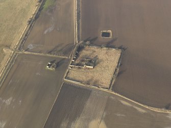 Oblique aerial view centred on the remains of the castle with the remains of the farmstead adjacent, taken from the SSE.