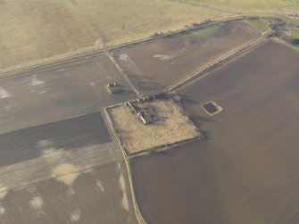 Oblique aerial view centred on the remains of the castle with the remains of the farmstead adjacent, taken from the E.