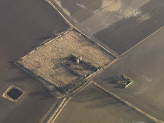 Oblique aerial view centred on the remains of the castle with the remains of the farmstead adjacent, taken from the NW.