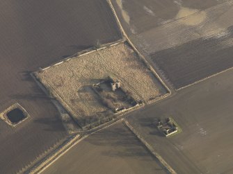 Oblique aerial view centred on the remains of the castle with the remains of the farmstead adjacent, taken from the W.